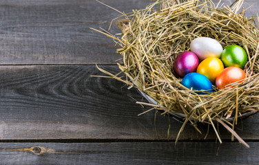 Easter eggs in the nest on rustic wooden background