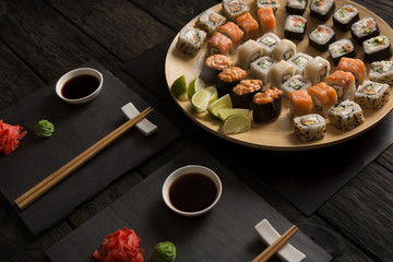 Set of salmon sushi and rolls on black background, top view