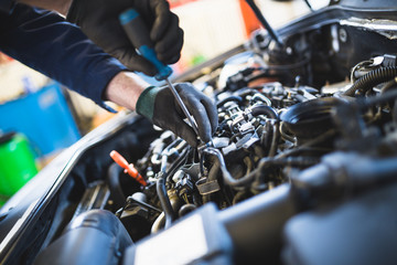 Obraz na płótnie Canvas Close up hands of unrecognizable mechanic doing car service and maintenance.