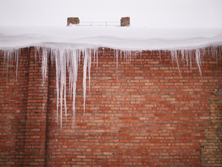 Brick wall. Wall of red brick. Icicles on a brick wall.
