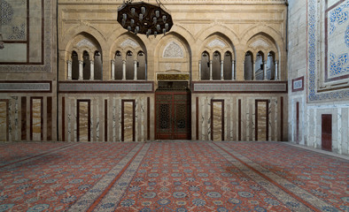 Obraz premium Interior shot of Al Rifaii Mosque (Royal Mosque) with iron chandelier, decorated marble wall and ornate wooden door, located in front the Cairo Citadel, Cairo, Egypt
