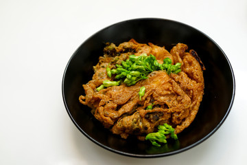 Thai omelette with green cowslip creeper in black dish with white background