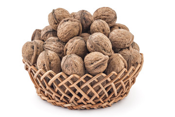 Dried walnuts in woven basket, on a white background