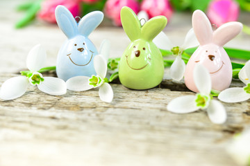 Osterhasen Trio auf einer Holzplatte mit Schneeglöckchen