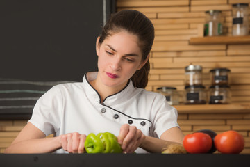 woman chef is slicing a green pepper