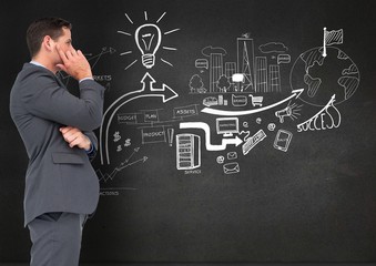 Businessman standing against business plan concept on blackboard