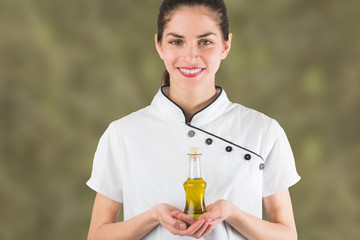 woman chef is holding a bottle of olive oil isolated in olive green background