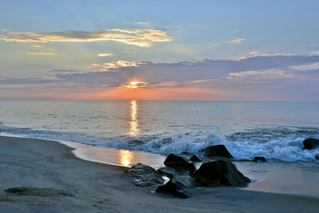 Fototapeta premium Rock Jetty on Beach Beneath A Summer Sunrise