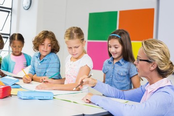 Teacher helping kids with their homework in classroom