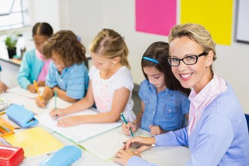 Fototapeta premium Teacher helping kids with their homework in classroom
