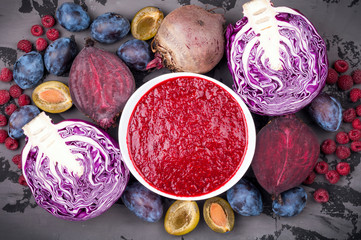 Smoothies bowl with purple fruit and vegetables on dark background. Healthy eating and diet concept. Top view