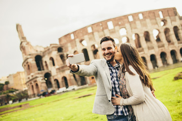 Young couple taking selfie in front of Colosseum in Rome, Italy