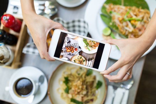 Mobile phone taking photo on food from top in restaurant