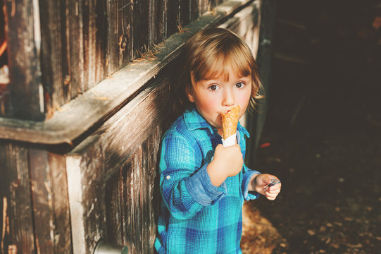 Adorable 3 year old blond boy eating ice cream outdoors