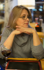 Blonde woman has dinner in japanese restuarant  with sushi and drink red wine