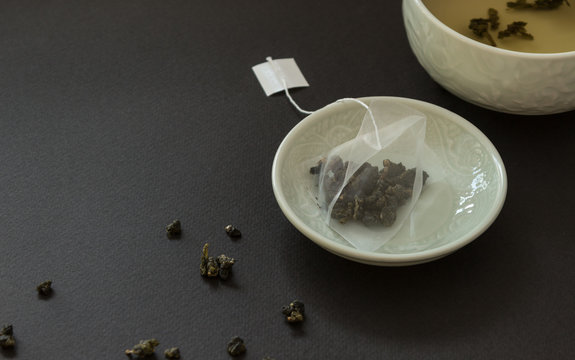 Tea bag in saucer on black background.