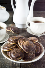 Homemade chocolate chip cookies and hot tea on wooden table.
