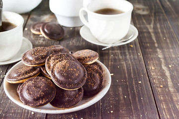 Homemade chocolate chip cookies and hot tea on wooden table.
