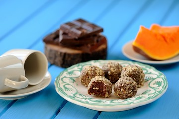 Homemade vegetarian truffles with pumpkin, chocolate and coffee cups on bright blue table