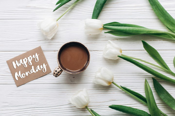 happy monday text sign on greeting card with tulips and morning coffee on white wooden rustic background with space for text. stylish flat lay with flowers and drink. hello spring. modern photo