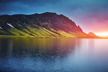 Fototapeta na wymiar Lake coast with mountain reflection at the sunrise, Iceland. treking in Iceland. Travel concept.