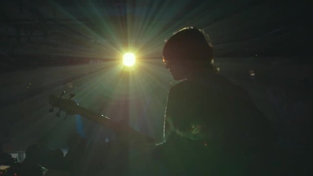 Silhouette of Guitar Player On Stage. Dark Background, Smoke, Spotlights, Back View In Modern Nightclub