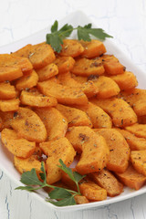 Butternut slices baked in spicy dressing on white plate