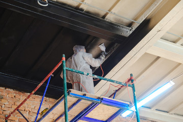 worker paints by spray gun