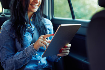 Woman using digital tablet computer and sitting in a car