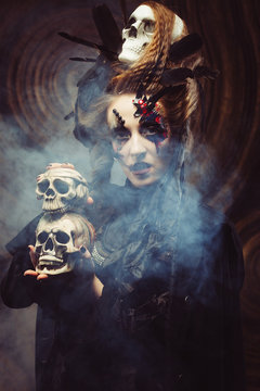 Young  witch hloding skull. Bright make up and  smoke-  halloween theme.