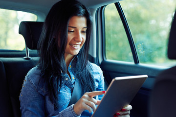 Smiling woman sitting in a car with tablet computer