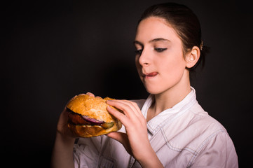 woman with a hamburger on a dark background
