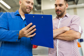 auto mechanic with clipboard and man at car shop