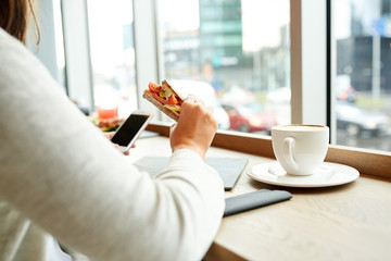 woman with smartphone and sandwich at restaurant