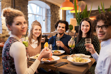 happy friends eating and drinking at restaurant