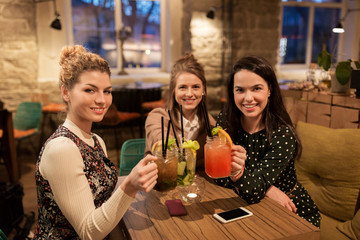 happy friends clinking drinks at restaurant