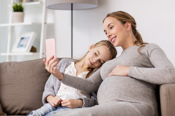pregnant woman and girl taking smartphone selfie