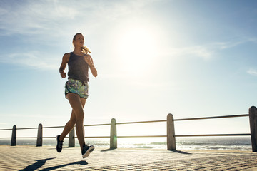 Jeune femme fitness jogging le long de la plage