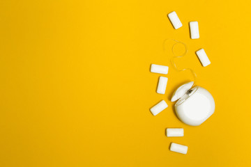 Chewing gum and dental floss on a yellow background. Space for text.