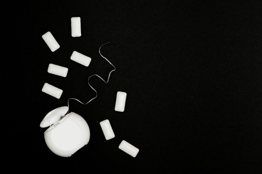 Dental floss and chewing gum cushions on a black background.