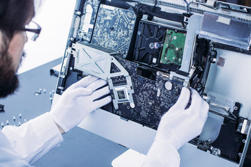 Process of computer repair. Engineer in white gloves disassembling computer.
