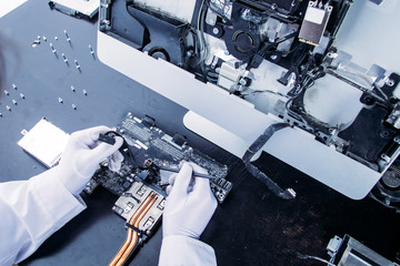 Process of computer repair. Engineer in white gloves disassembling computer.