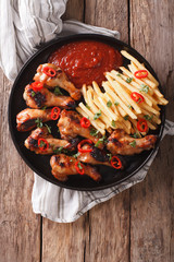 Delicious barbecue chicken wings with french fries and ketchup close-up. Vertical top view