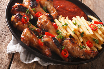Spicy BBQ chicken wings with french fries and sauce close-up. horizontal
