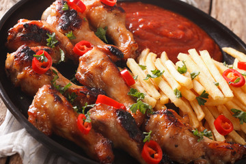 Delicious barbecue chicken wings with french fries and ketchup close-up. horizontal