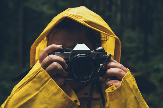 Person in yellow raincoat using camera