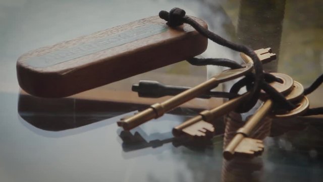 Metal Keys with Wooden Key ring come into focus on glass table