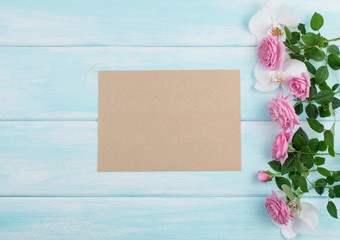 Wooden background with roses and orchid and empty notebook with place for text