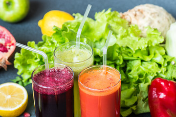three glasses of different fresh juice. Beet, carrot and kiwi juices on grey background