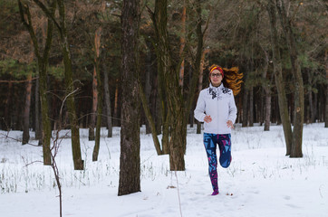 Sport young woman running in the winter forest.